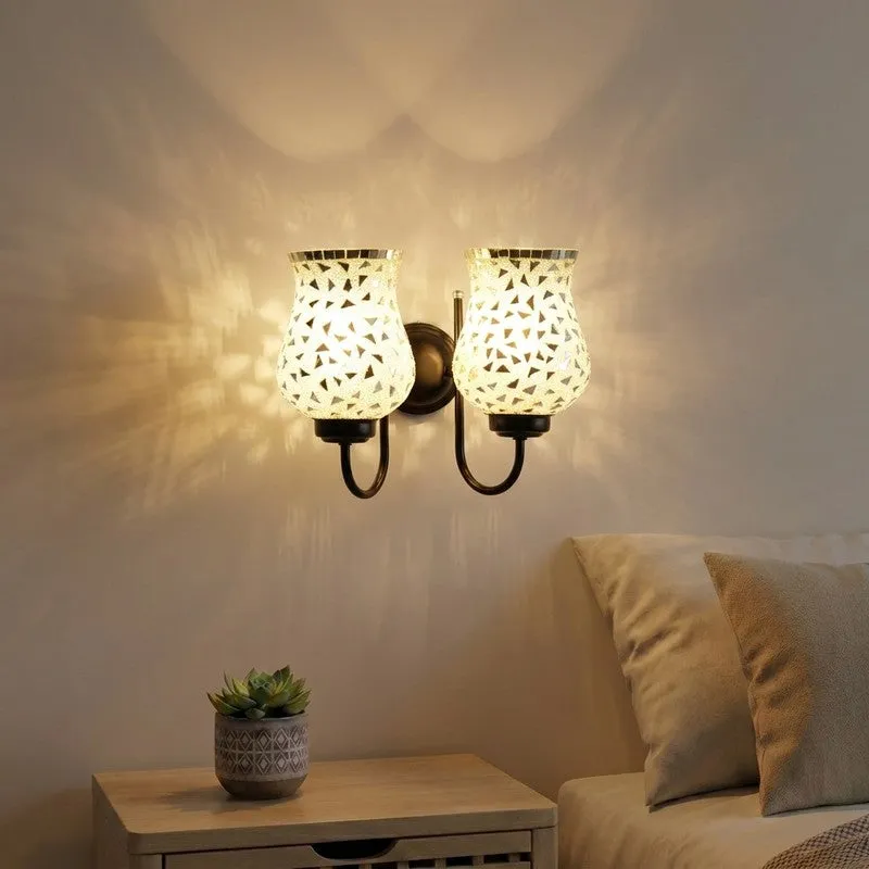 Dual wall lamp with two mosaic glass bell shades lit on a wall