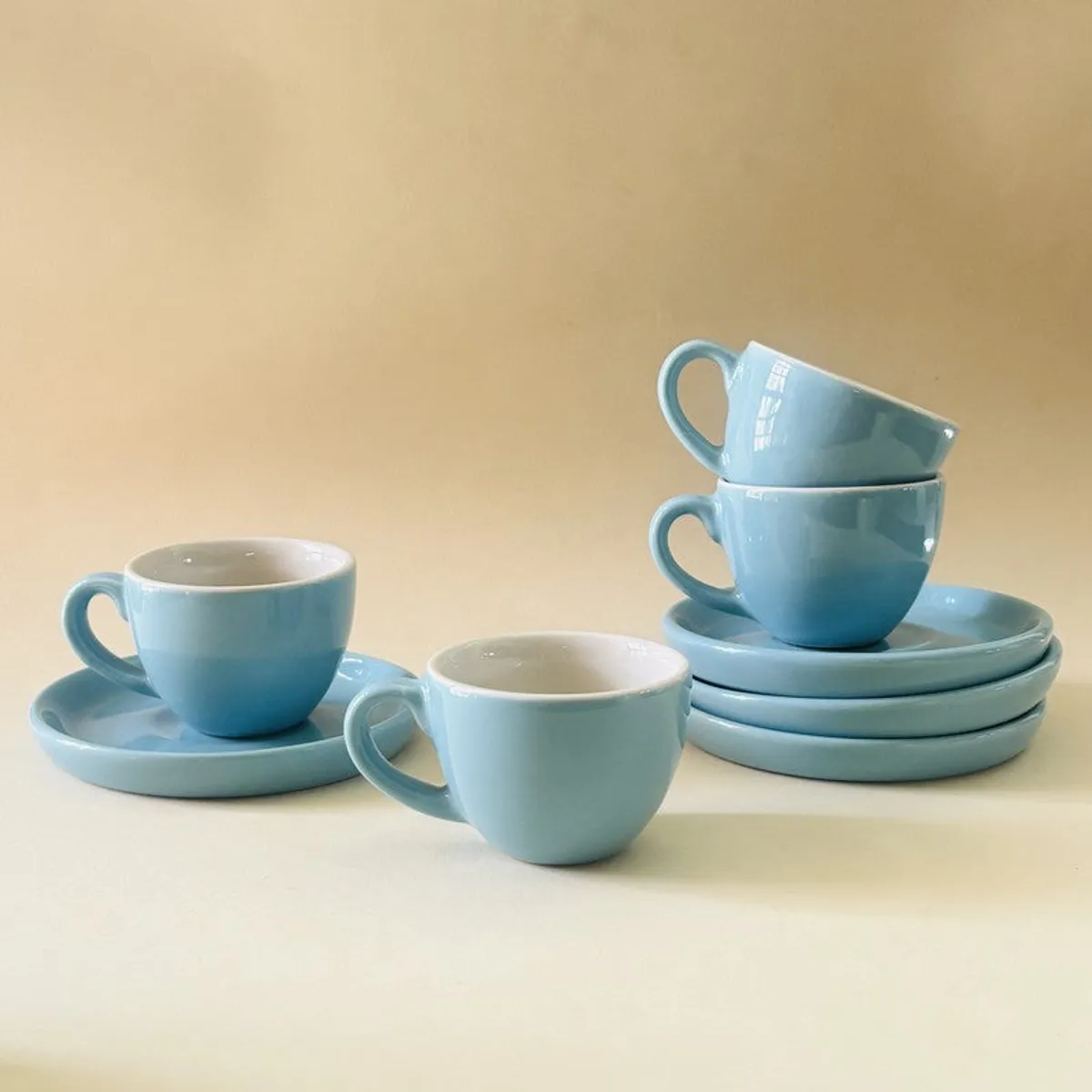 Blue ceramic cups and saucers arranged against a light neutral background