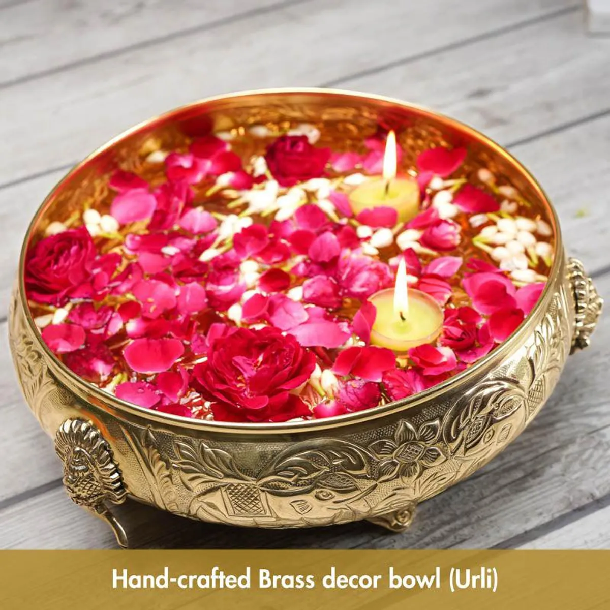 Close-up of the gold urli filled with pink rose petals, white flowers and candles.
