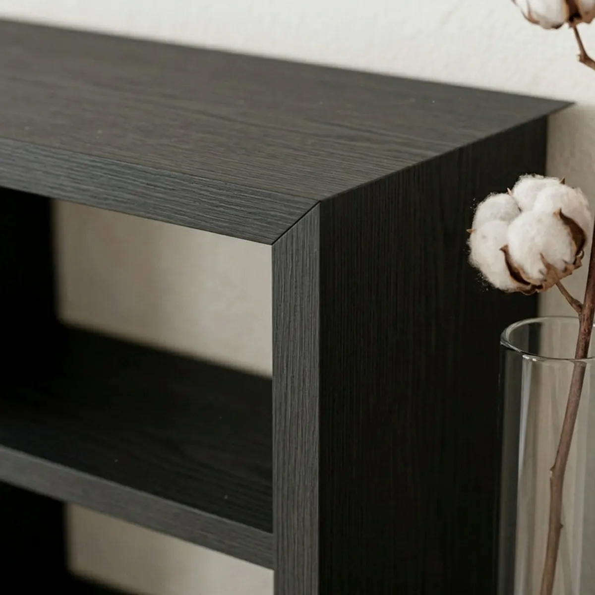 Close-up of the black shelf's matte surface and clean-lined corner detail.