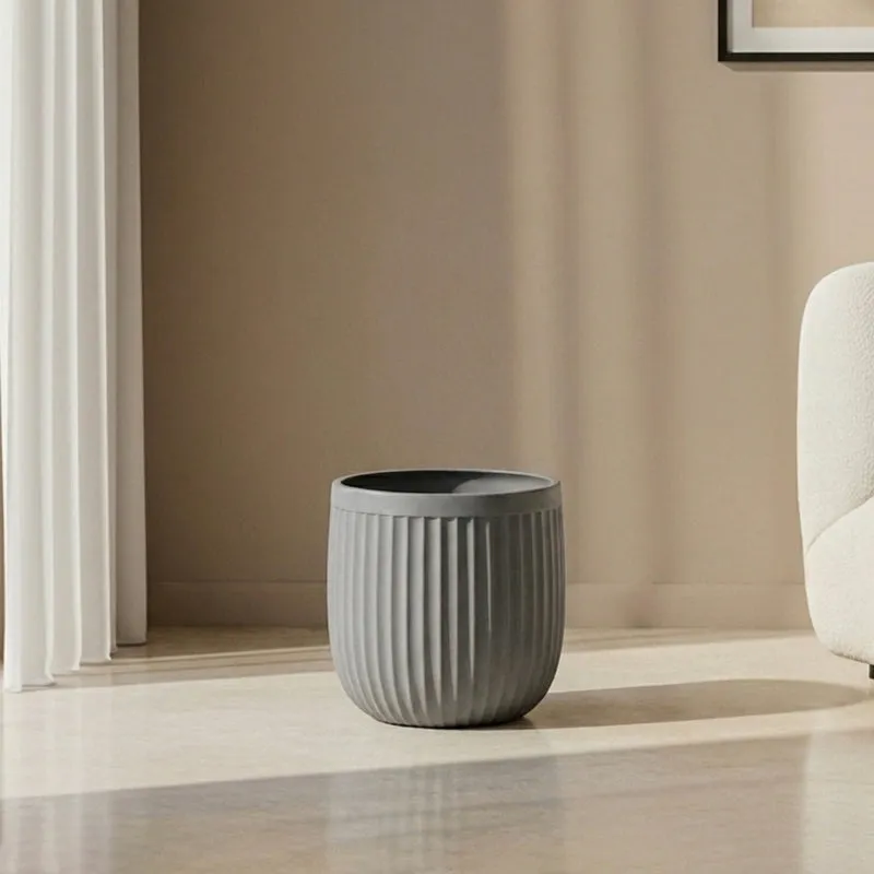 Empty grey cylindrical ribbed planter on a living room floor.