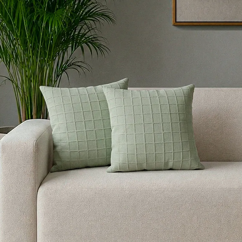 Two light green textured cushion covers styled on a cream sofa