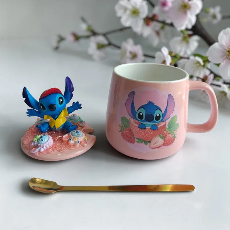 Pink Stitch mug with strawberry motif, figurine lid and gold spoon on a white surface