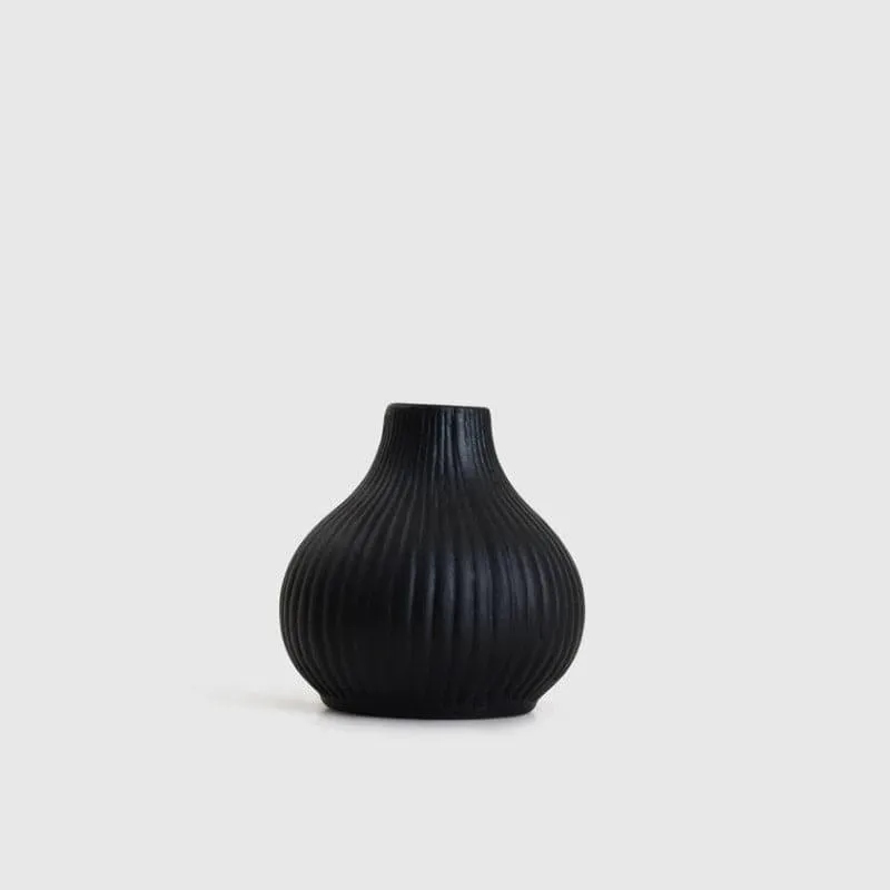 Black ribbed urn vase against a plain light background