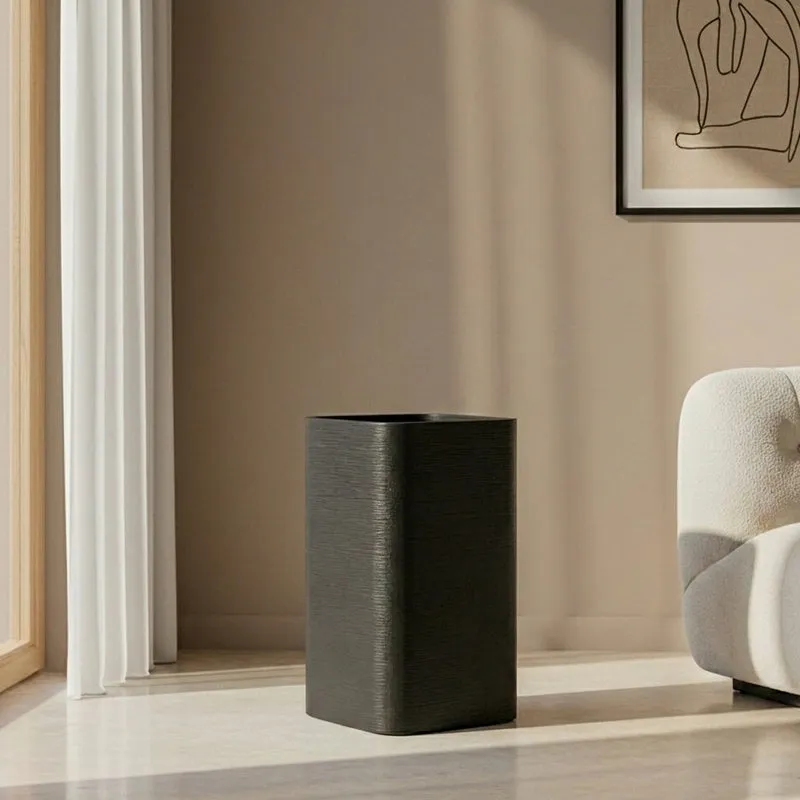Empty black rectangular floor planter beside a modern armchair