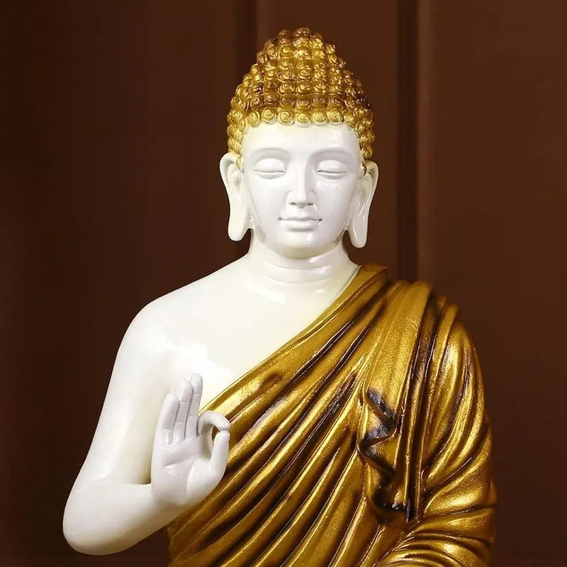 Close-up of white and gold Buddha idol with draped robe detailing