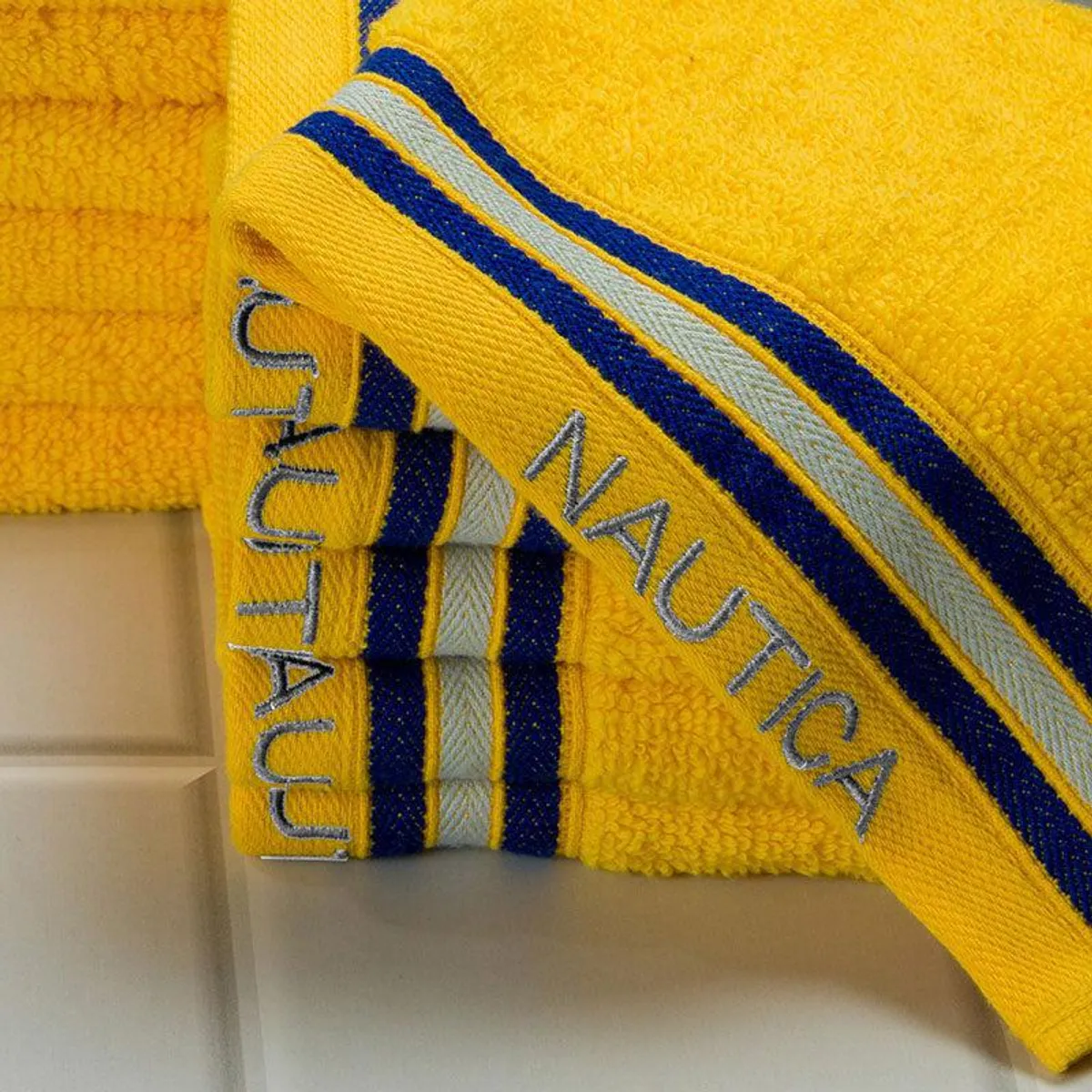 Close-up of a yellow face towel showing blue and white striped edging