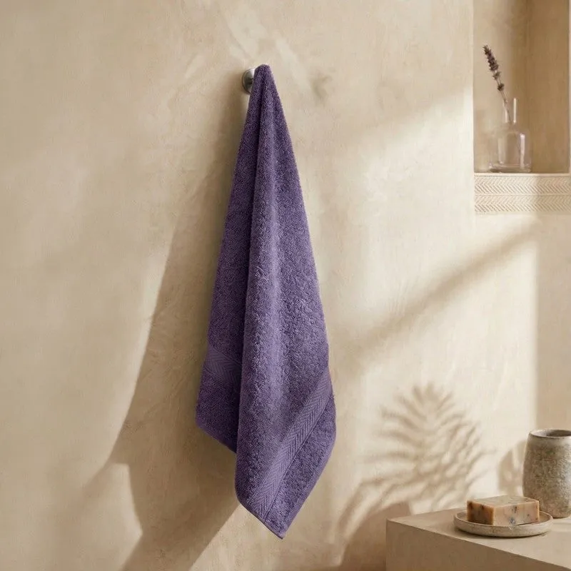 Purple bath towel hanging on a wall hook in a bathroom setting