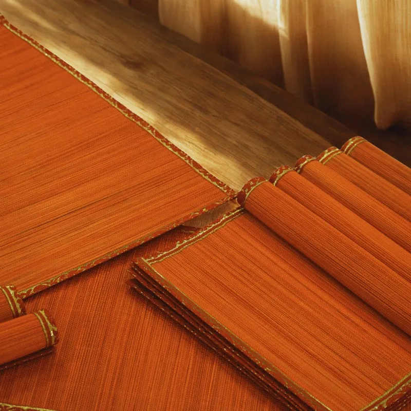 Close-up of orange textured table mats with decorative zari-edged borders