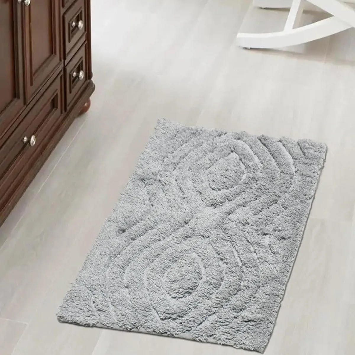 Grey rectangular bath mat with raised pattern on a light floor