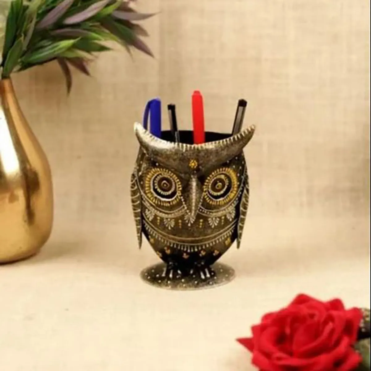 Owl pen stand holding colourful pens, styled beside a vase and red rose