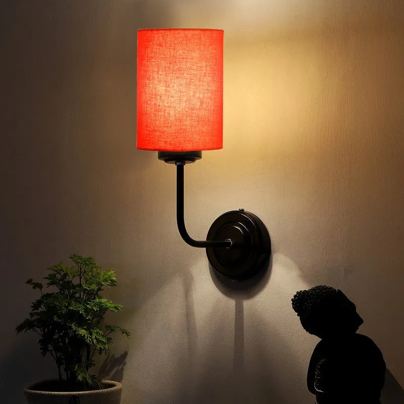 Orange cylindrical wall lamp glowing warmly on a dark wall