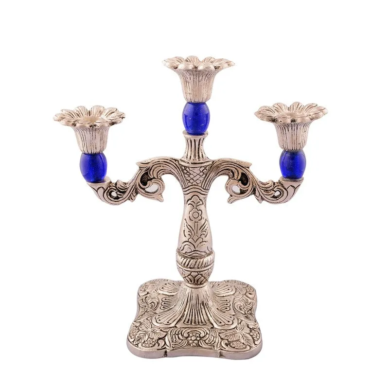 Front view of an ornate silver-toned candle holder with blue accents