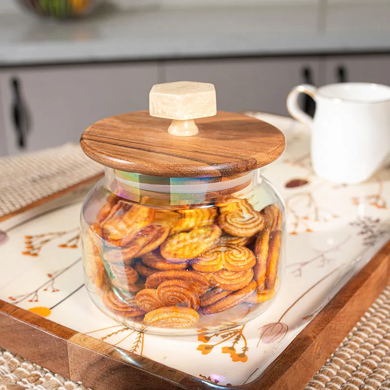Iridescent glass jar with wood lid filled with cookies on a serving tray