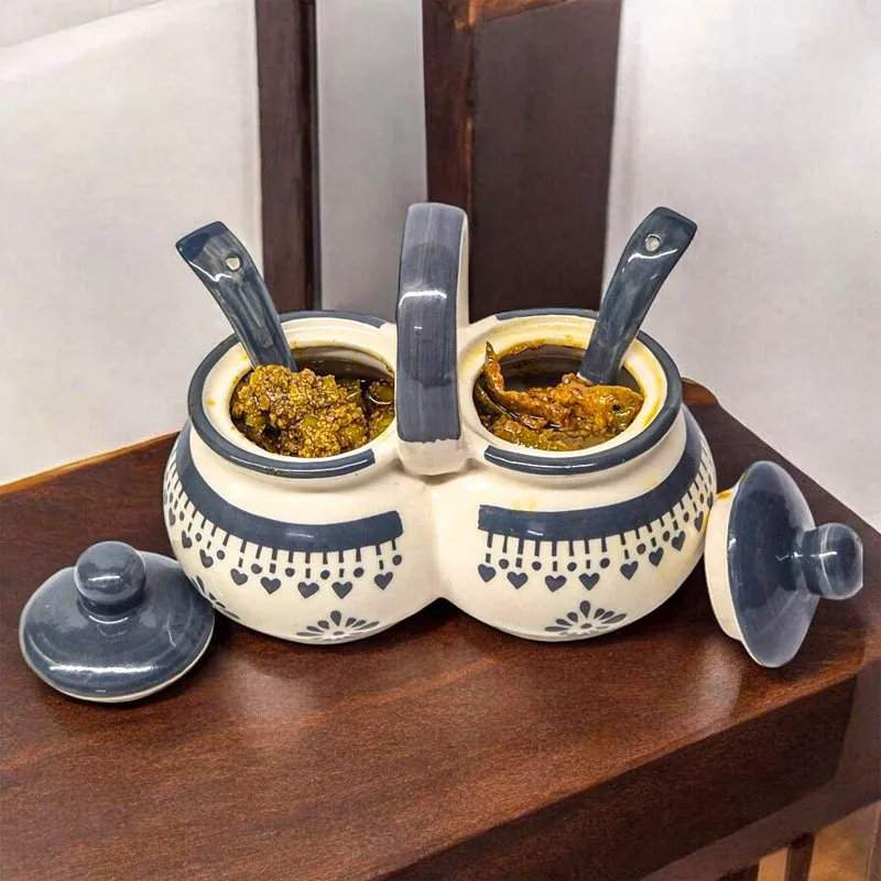 Open dual condiment jar with spoons and blue and white decorative lids.