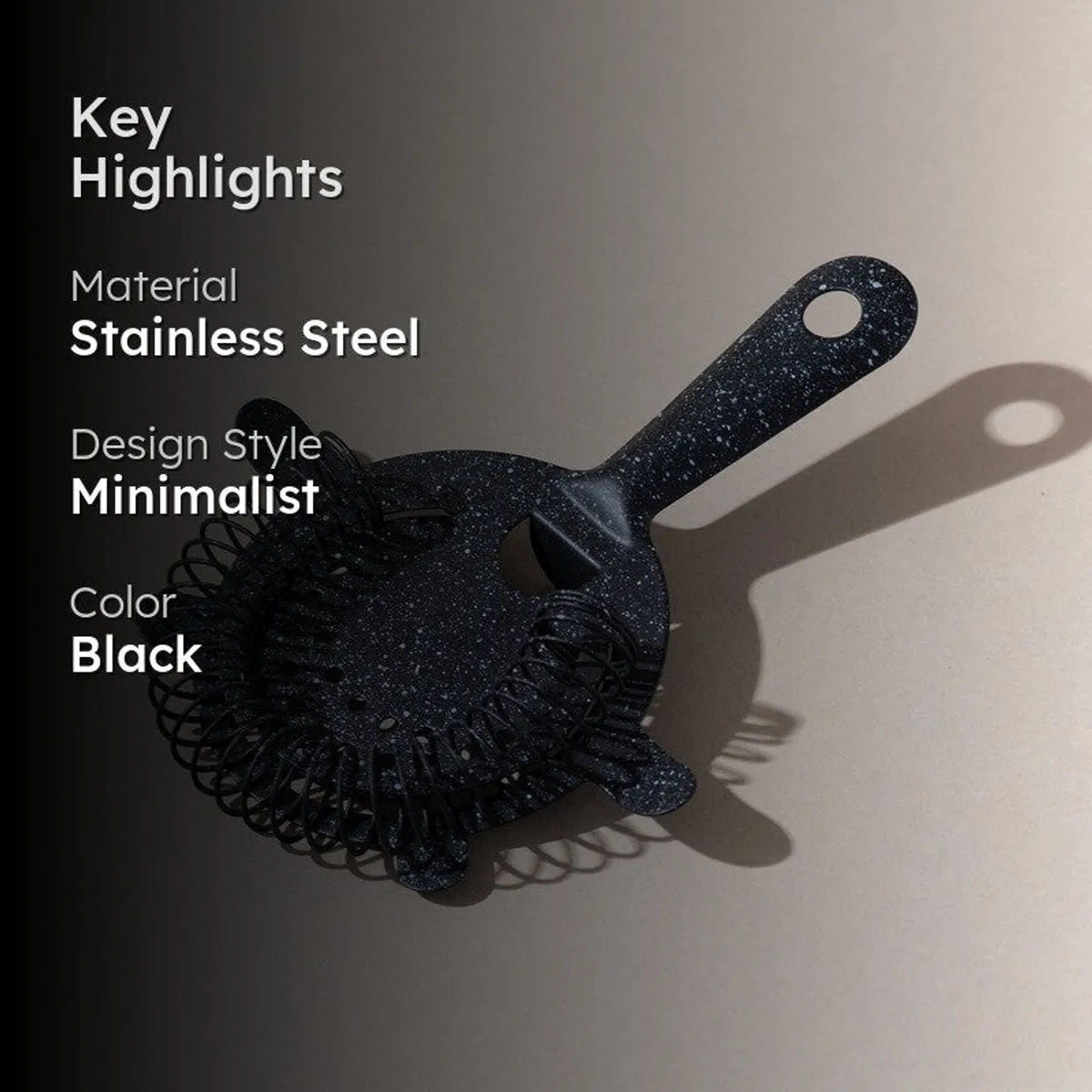 Speckled black cocktail strainer displayed on a dark neutral background