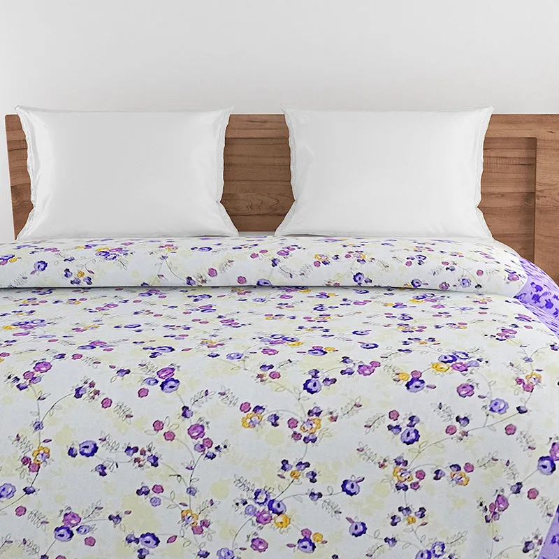 White floral comforter with purple edging styled in a bedroom