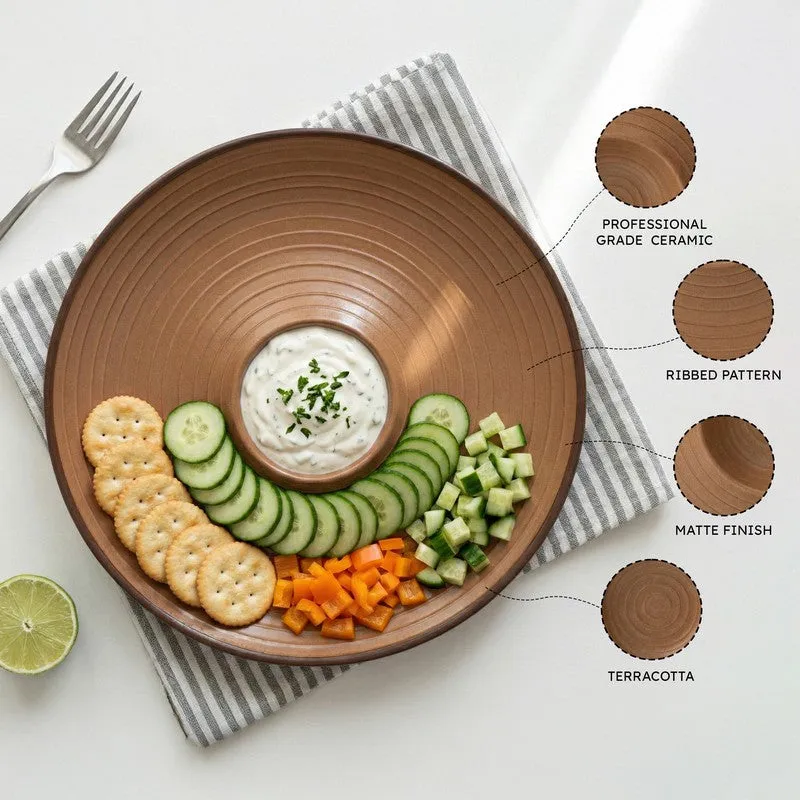 Brown ribbed ceramic platter arranged with vegetables, crackers and a central dip bowl