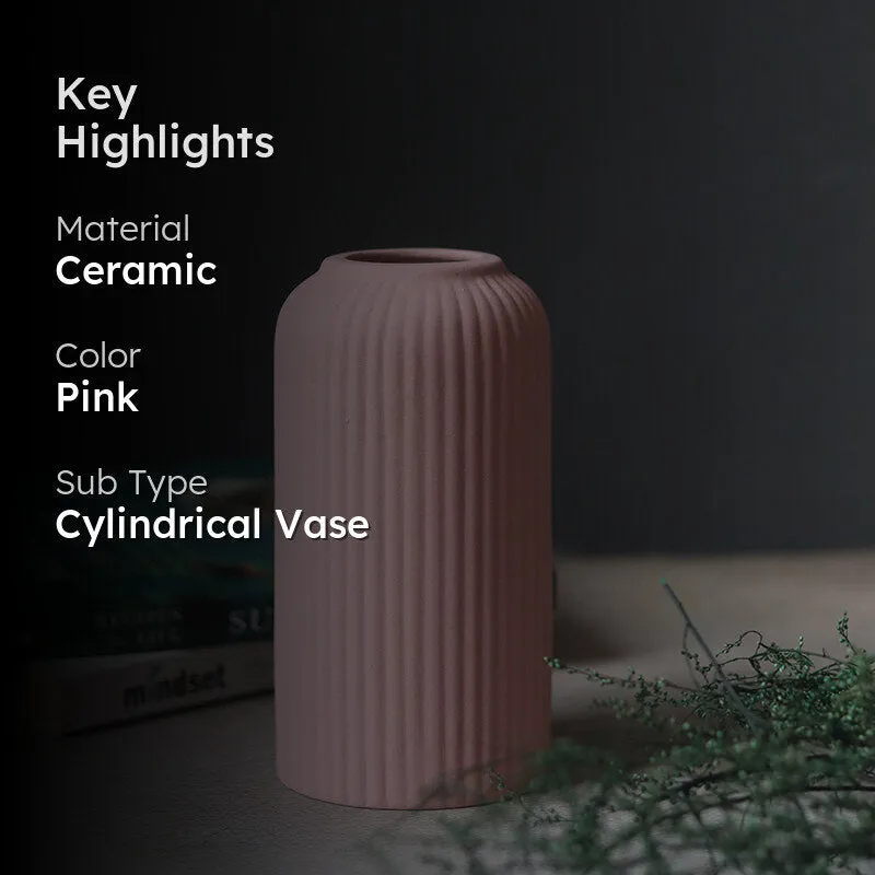Pink ribbed vase on a tabletop with a dark overlay and styling props