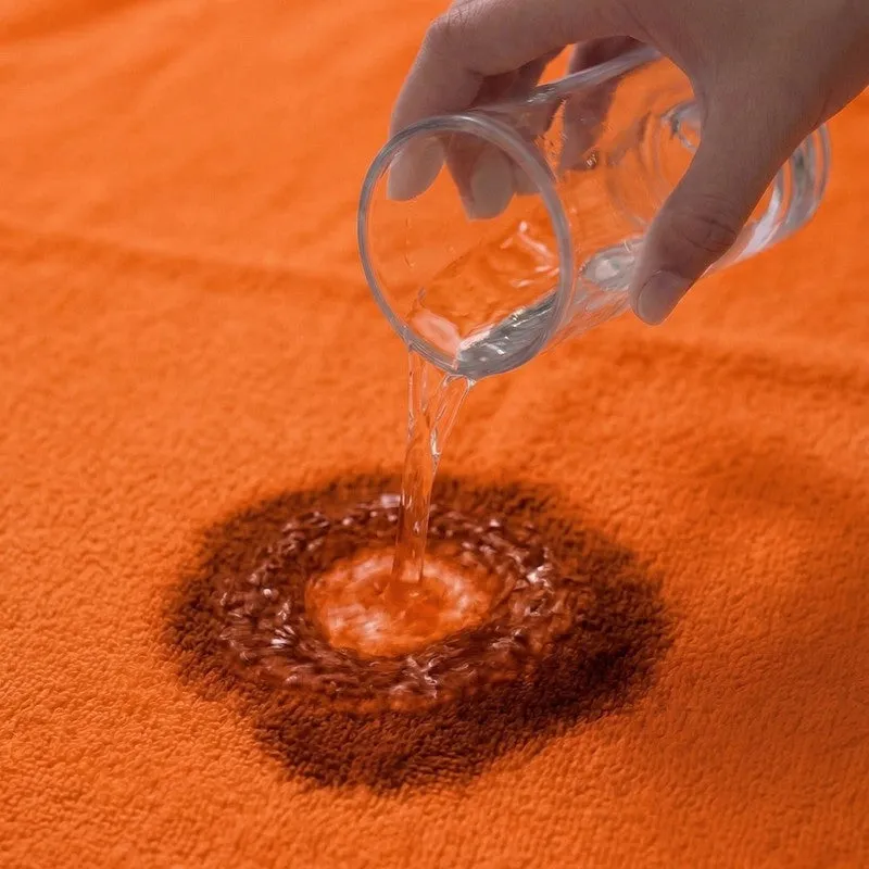 Water being poured onto the absorbent surface of an orange bath towel