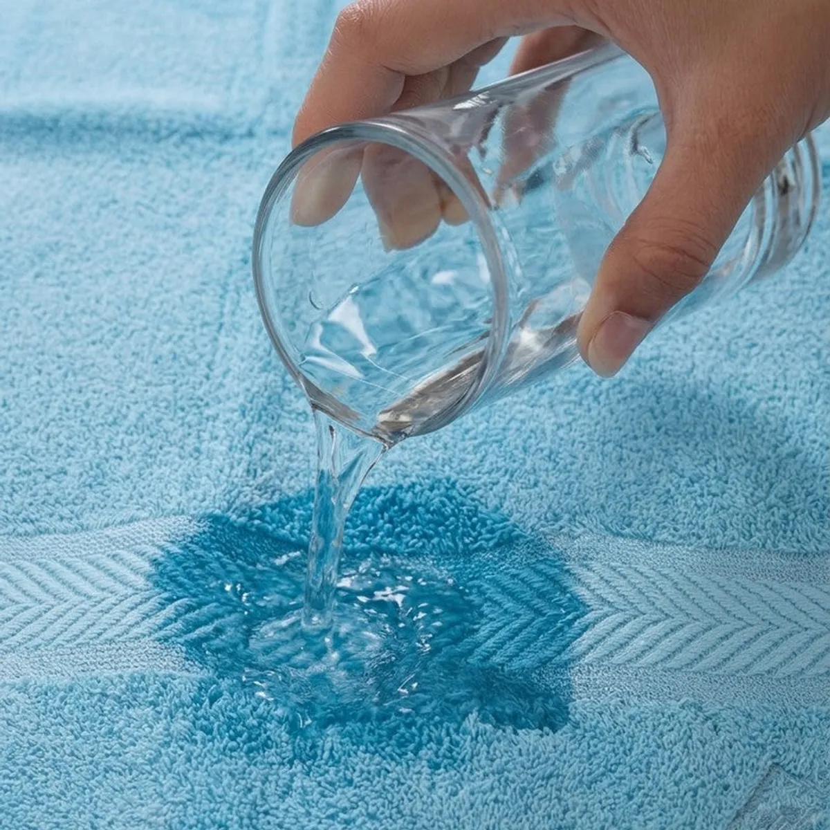 Water being poured onto the absorbent surface of a dust blue bath towel