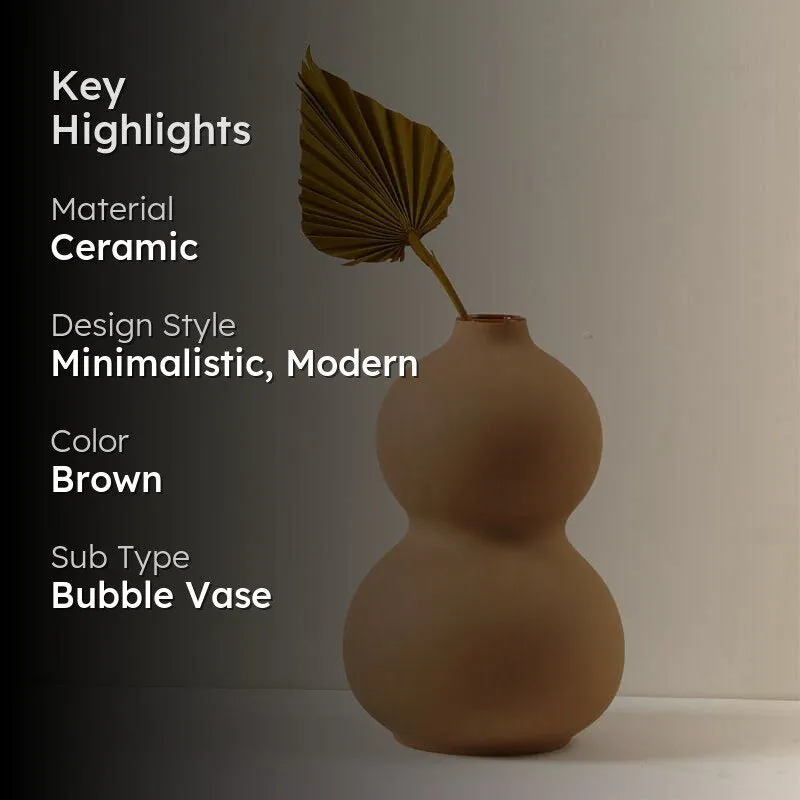 Brown ceramic bubble vase with a dried leaf against a neutral backdrop