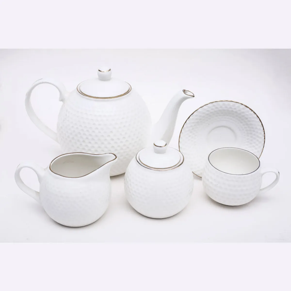White textured tea set with gold accents, including teapot, cups, milk pot and sugarpot