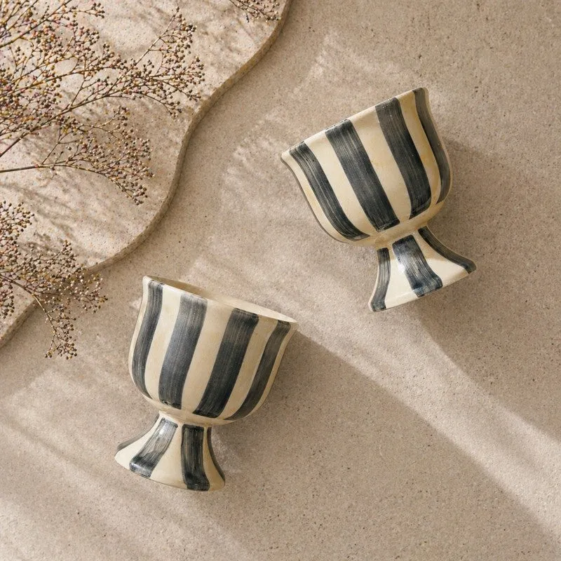 Top view of two striped pedestal dessert cups on a textured beige surface
