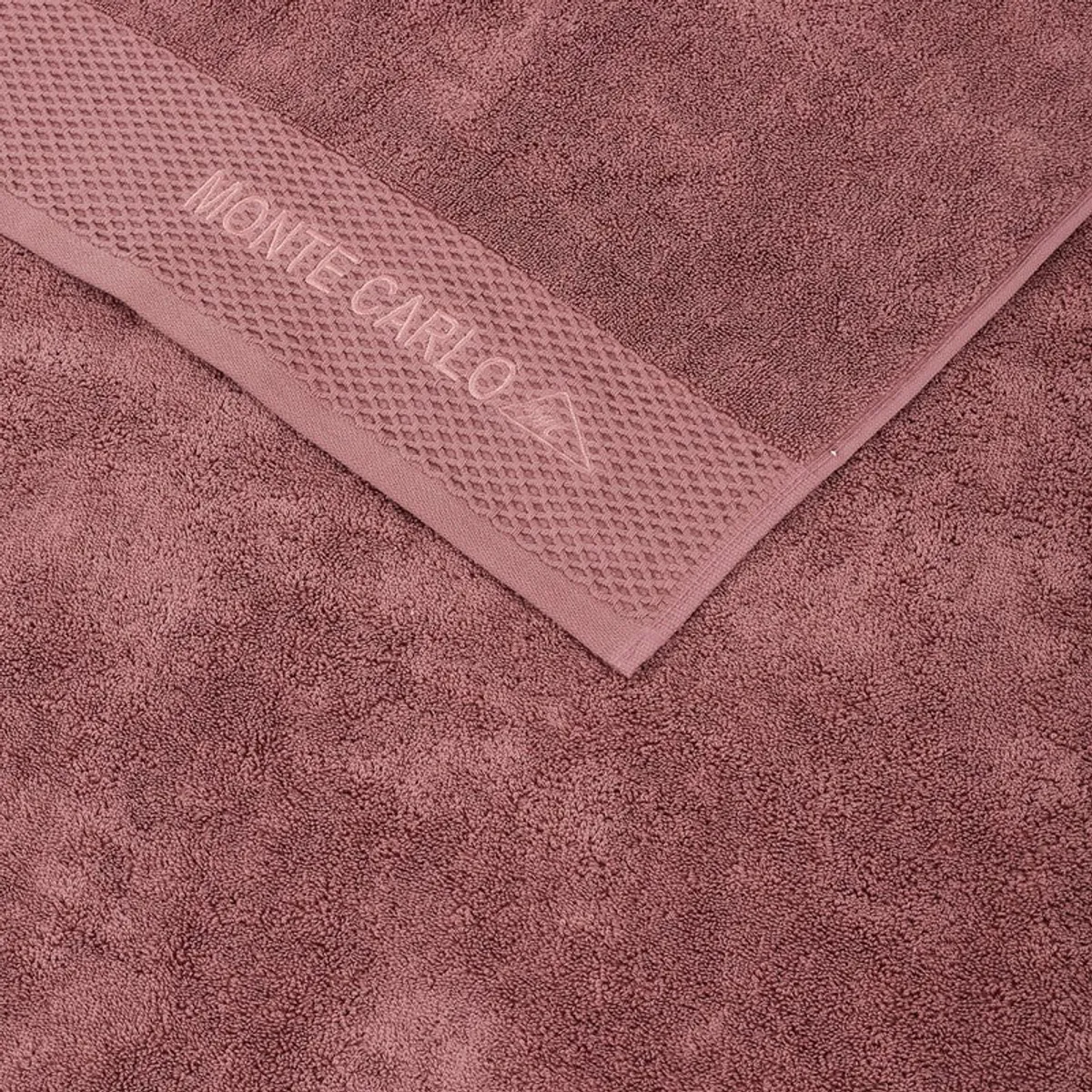 Close-up of dusty pink towel texture and branded border detail