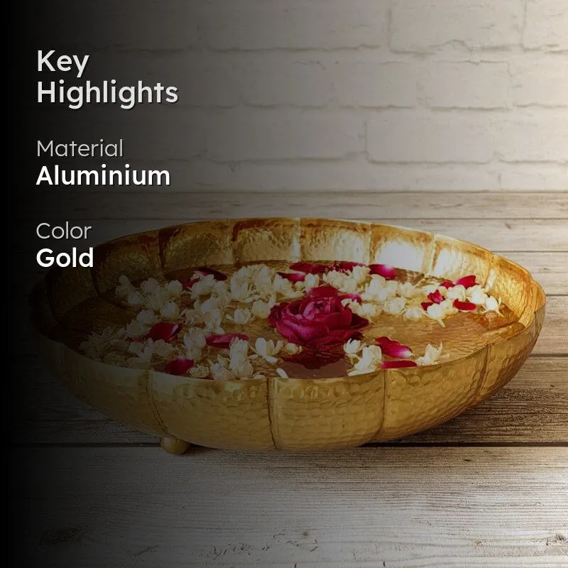 Gold hammered urli with floating flowers against a brick backdrop