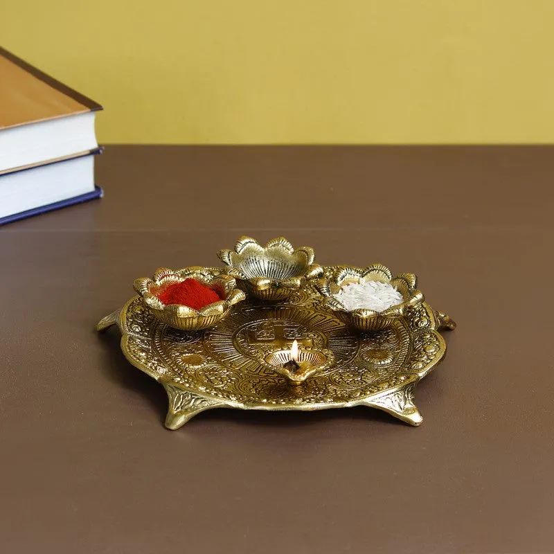 Gold decorative pooja thali with flower-shaped holders and diya space on a tabletop