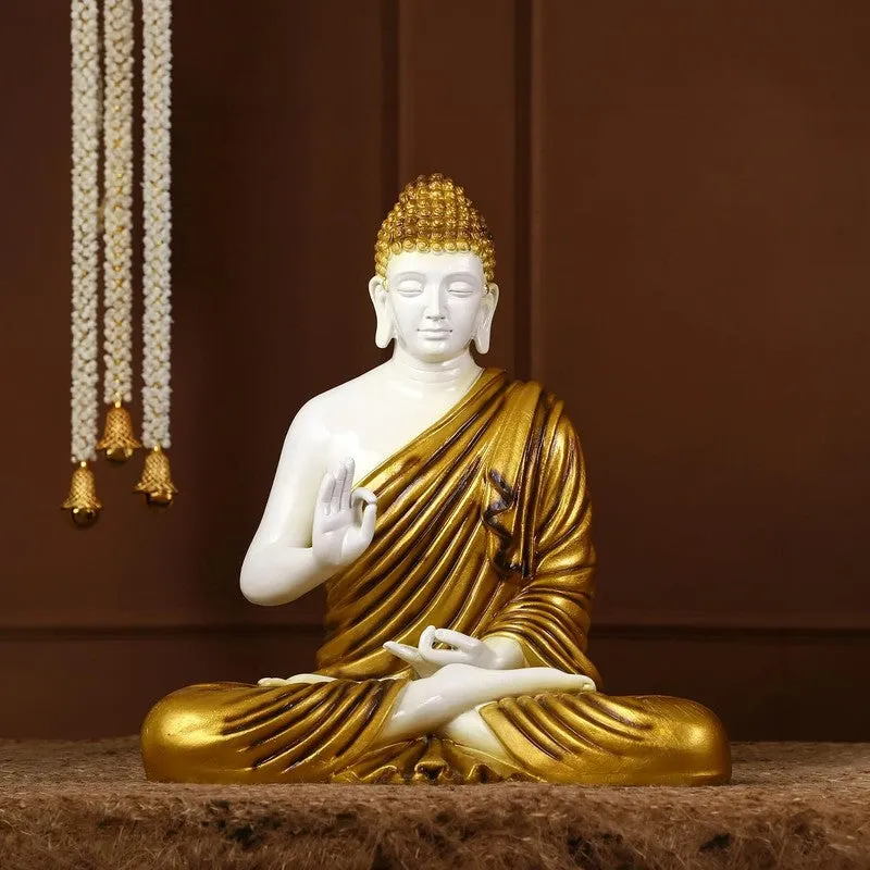 White and gold Buddha marble idol in a seated pose on a brown surface