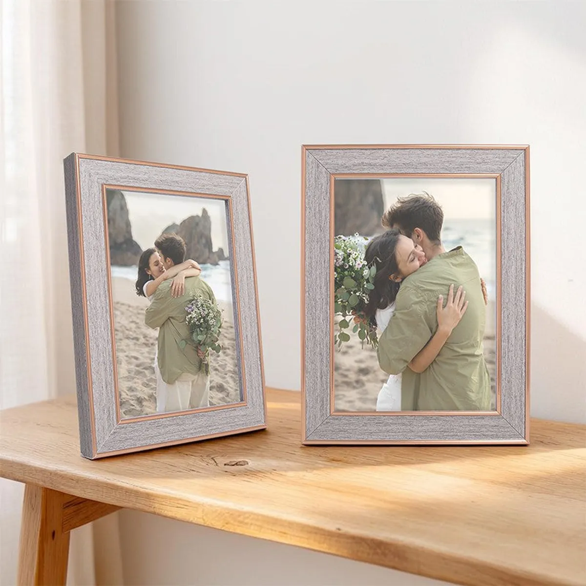 Pair of grey and gold photo frames displayed on a wooden table