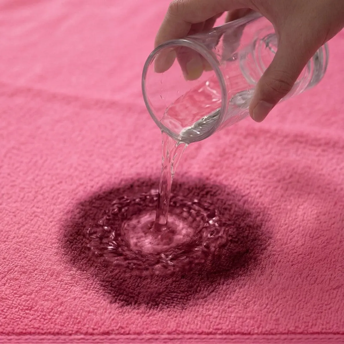 Water being poured onto the absorbent surface of a pink bath towel