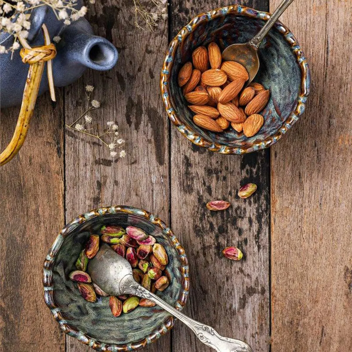 Top view of a rippled snack bowl filled with almonds beside another bowl of pistachios