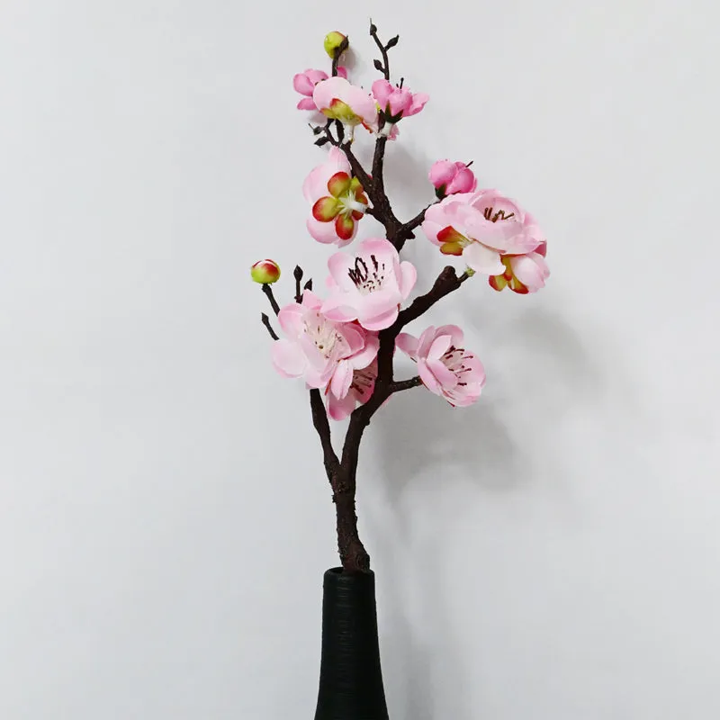 Pink artificial plum blossom stick displayed in a black vase