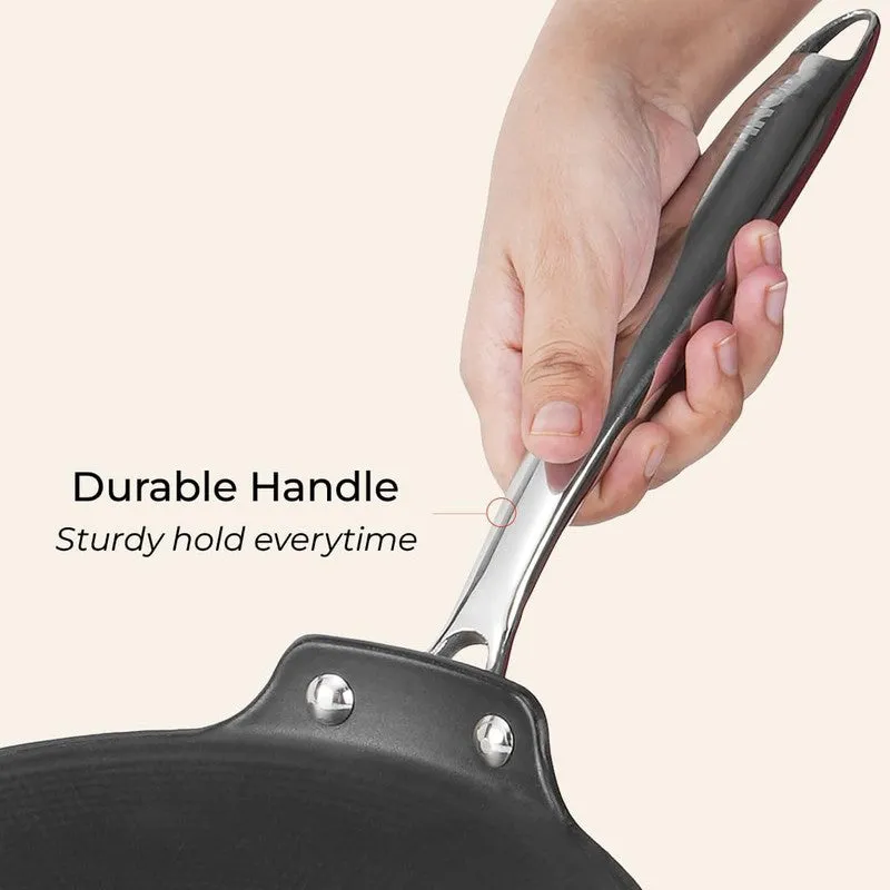 Hand holding the silver handle of the black roti tawa