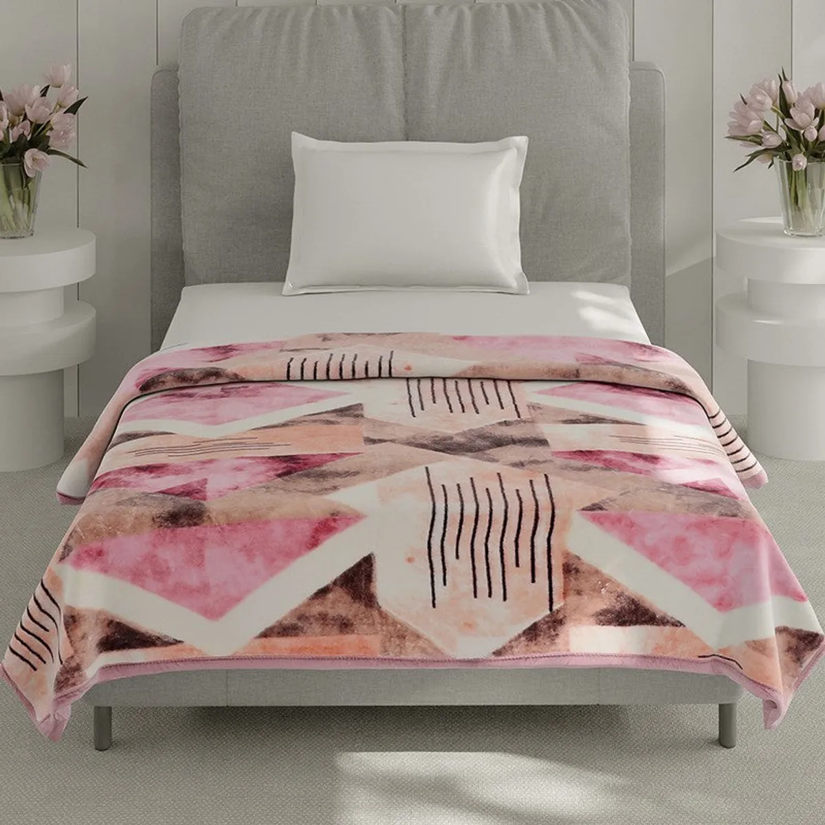 Blush geometric blanket draped over a bed in a bright bedroom