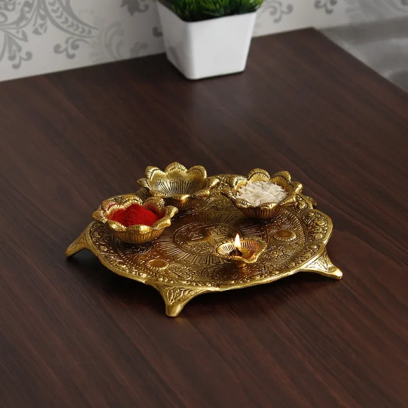 Gold round pooja thali with ornate detailing and flower-shaped holders on a wooden table