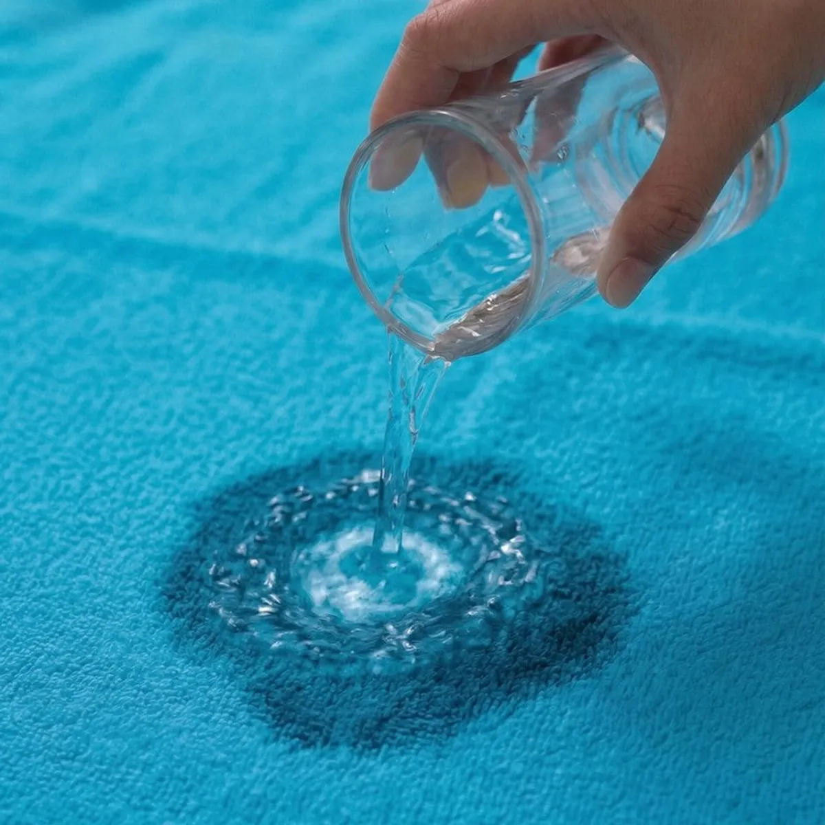 Water being poured onto a blue towel close-up.