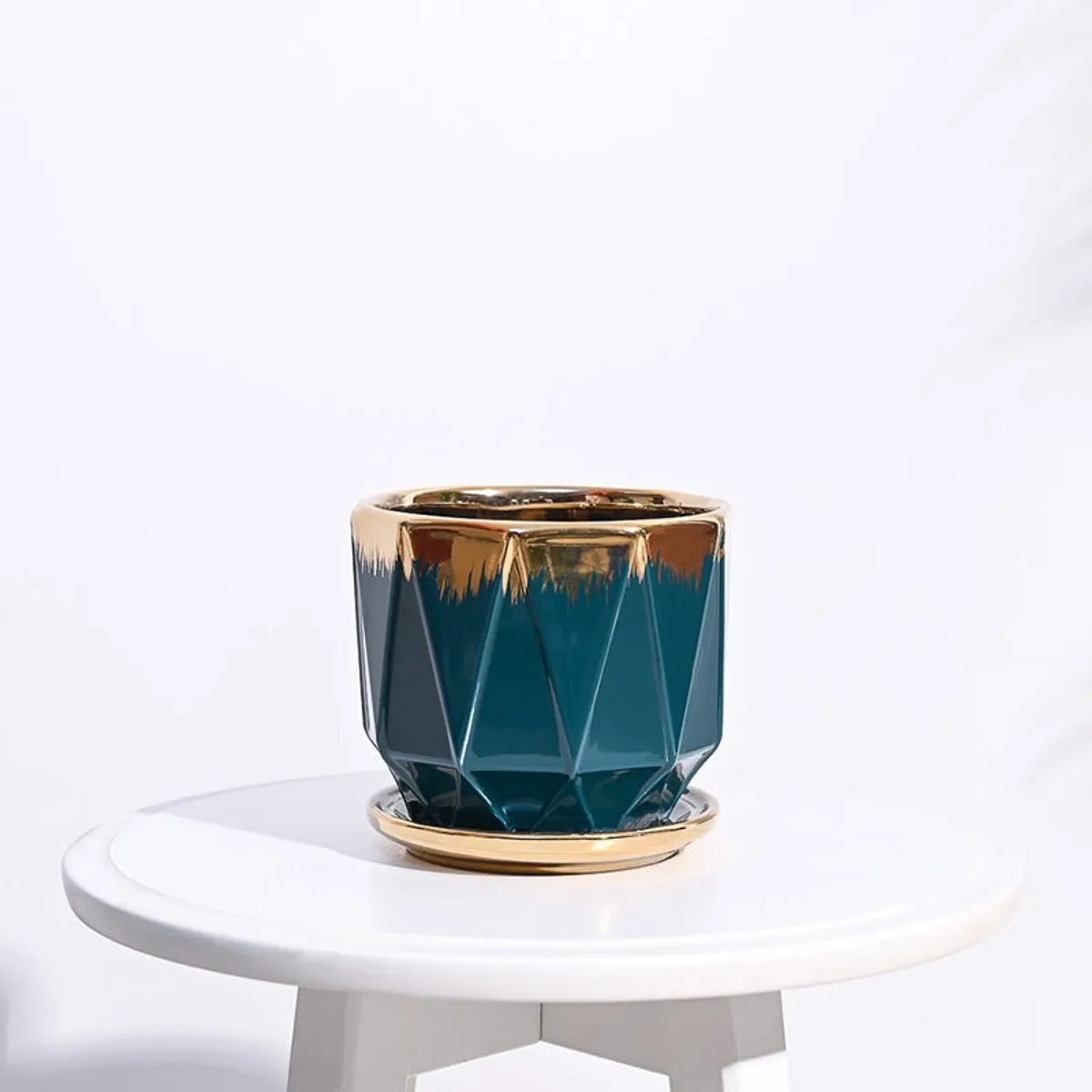 Blue and gold geometric ceramic planter displayed on a white round table.