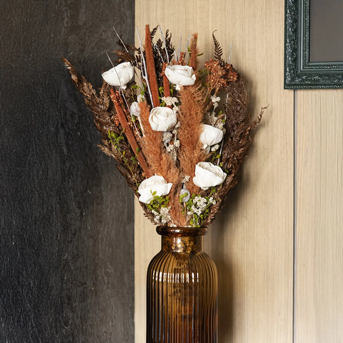 Dried flower bouquet with white blooms and earthy stems in an amber ribbed vase