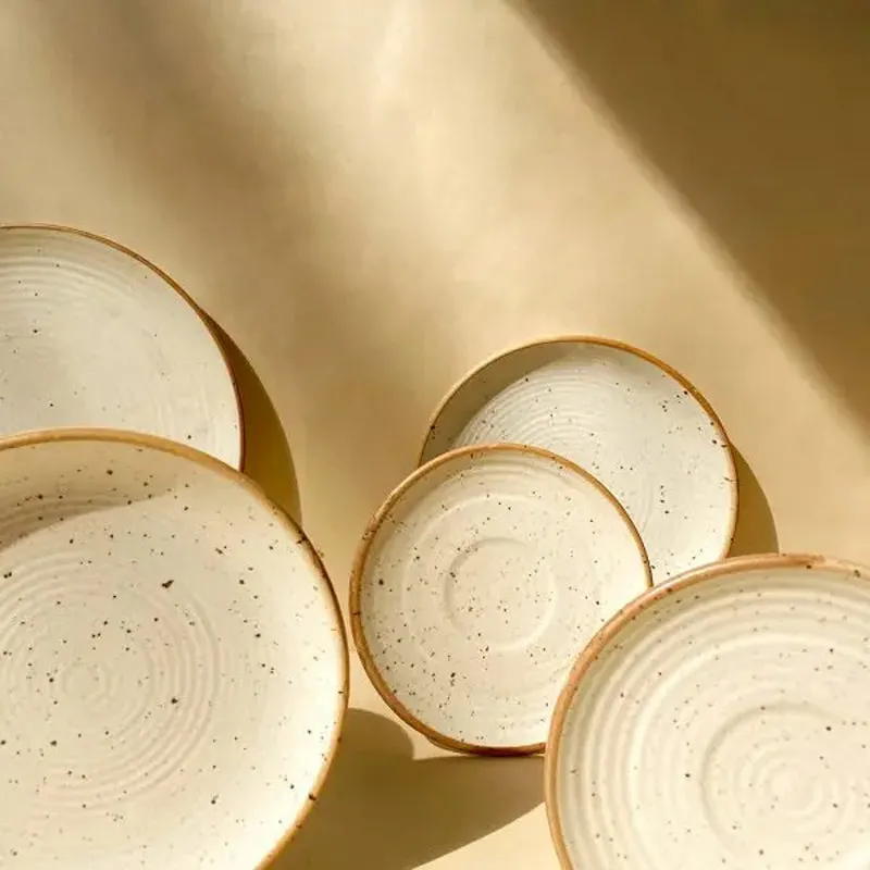 Close view of speckled warm white ceramic plates in assorted sizes