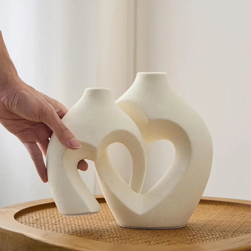 Two white ceramic vases with heart-like cut-out centres on a tray