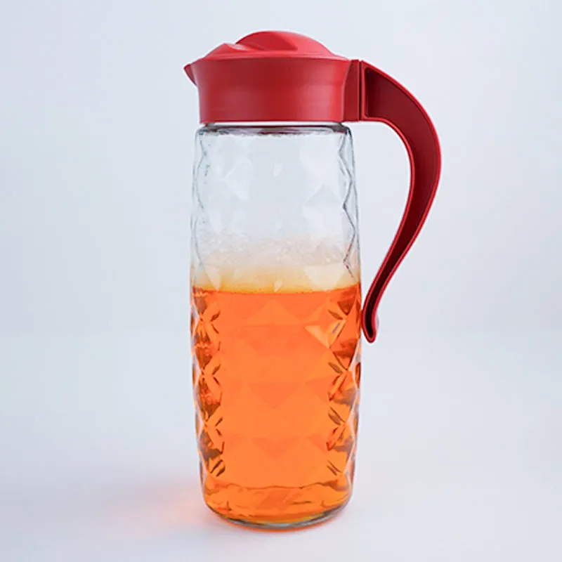 Transparent glass jug with red lid and handle on plain background