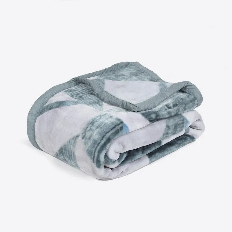 Folded pink and green geometric blanket showing its soft surface
