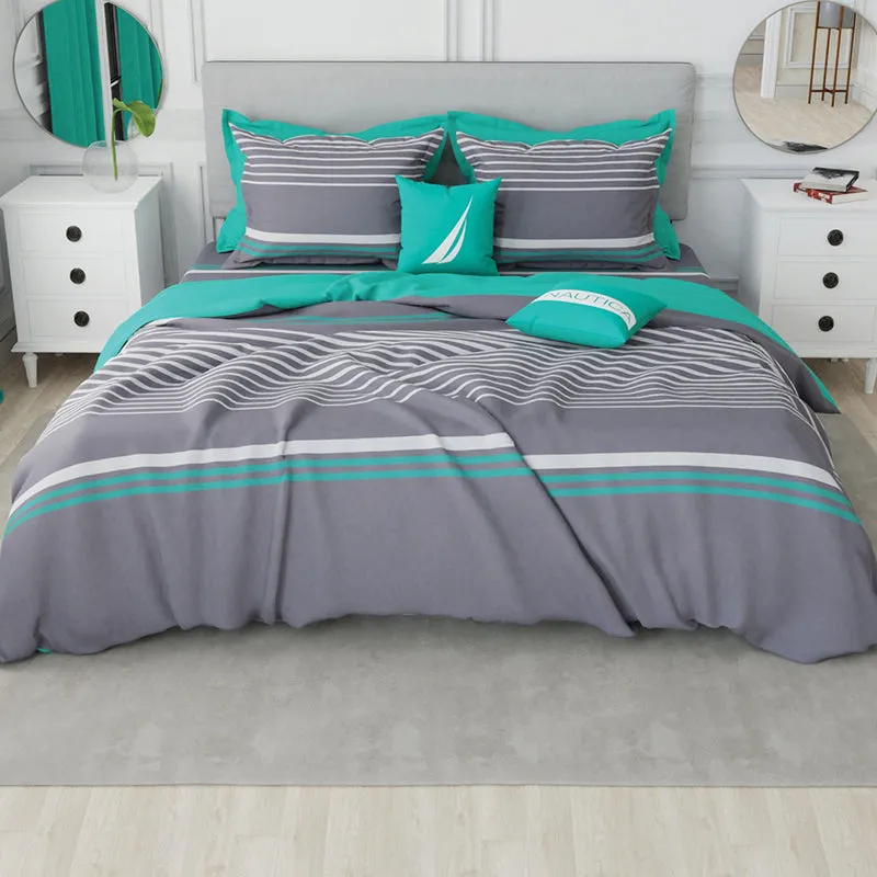 Grey and teal striped bedding styled with matching pillows on a bed