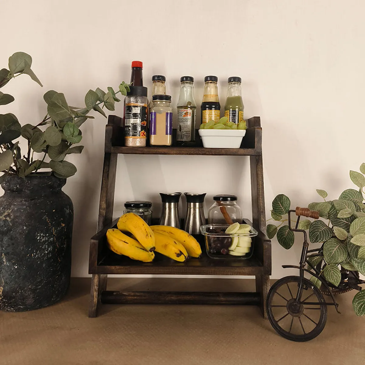 Wooden shelf ladder holding kitchen jars, fruit and condiments