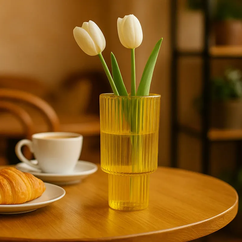 Yellow ribbed glass totem vase with tulips on a round wooden table