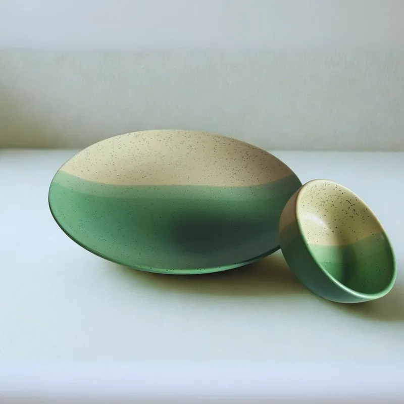 Green and beige ceramic plate and bowl arranged together against a light background